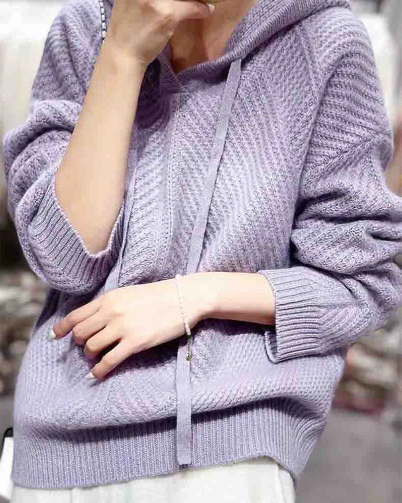 Woman lounging in the 100 % Wool Gentle Knitted Hoodie, 19.5-micron superfine Merino drapes like jersey—your cozy yet breathable 45-65 °F fall-through-spring essential.