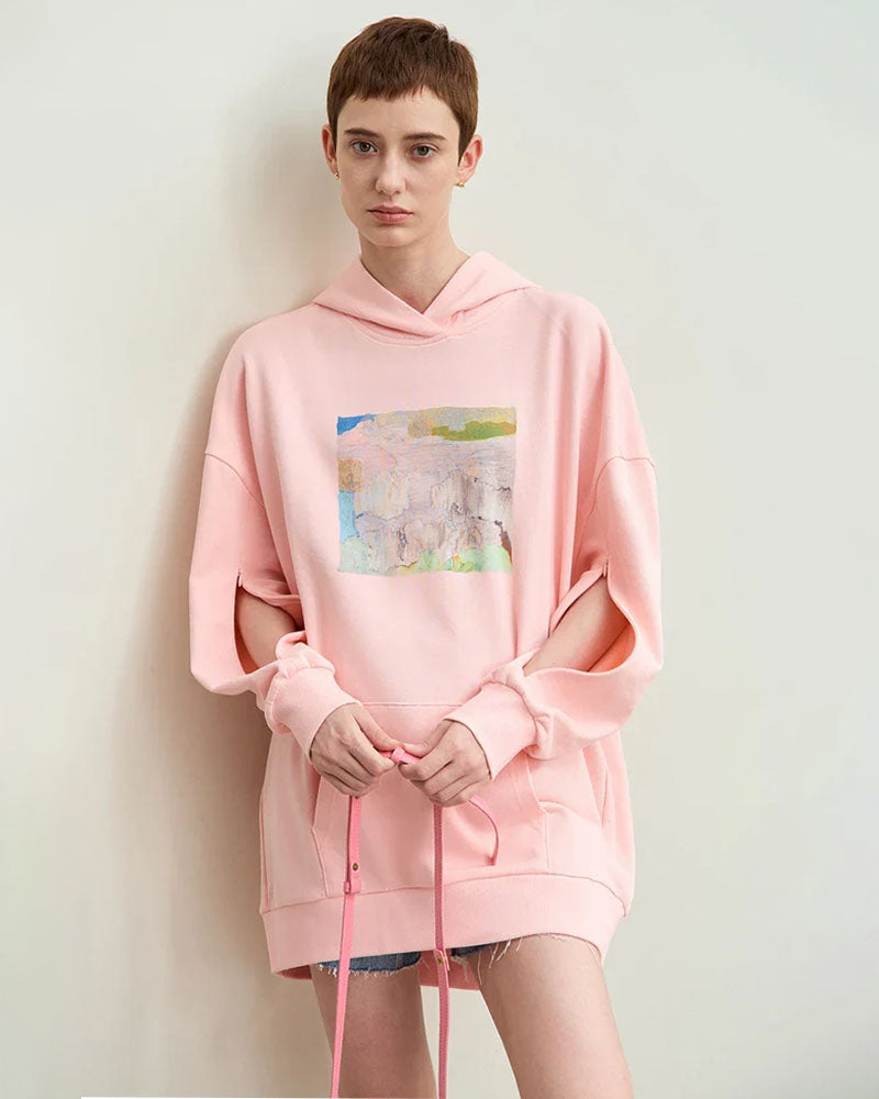 Street-shot of unisex hoodie splashed with surreal blue-green brushstrokes, oversized fit turns everyday fleece into walking gallery wall for fall-to-spring outfits.