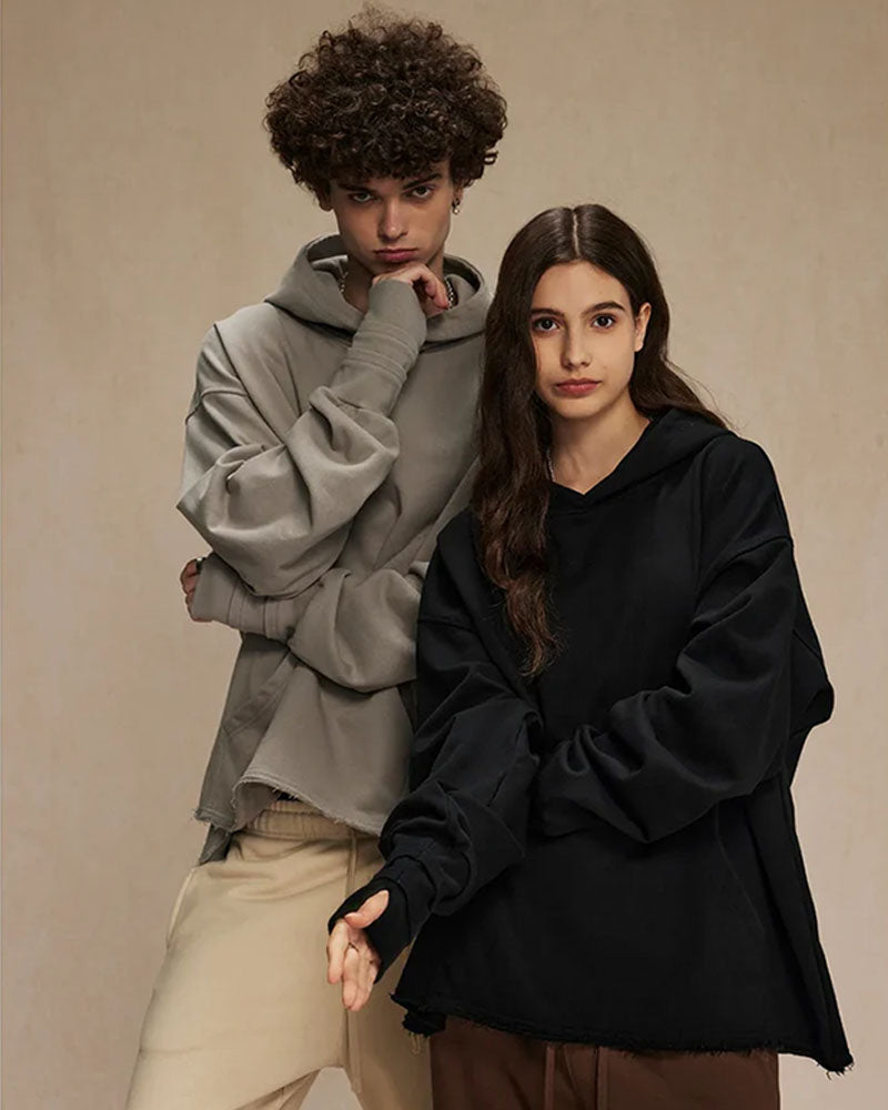 Woman lounging in a sand-beige loose 100 % cotton hoodie, airy French-terry fabric and dropped shoulders give relaxed 90s vibes—perfect breathable layer for 60-75 °F spring-fall days.