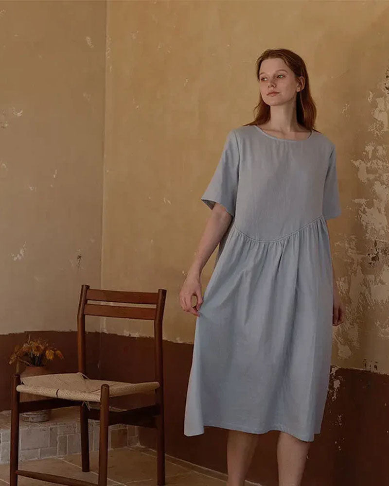 Woman drifting off in a breathable white cotton nightie, tag-free round neck and knee-length drape deliver spa-level softness for sensitive skin.