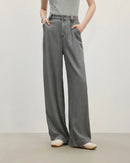 Woman walking city streets in light-wash draped wide-leg denim pants, soft cotton blend flows with each step—your go-to relaxed layer for 60-75 °F spring-fall weekends.