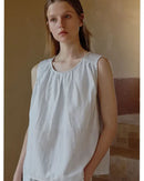 Woman relaxing in a pale-striped cotton-blend loungewear set, breathable jersey tee and drawstring shorts keep you cool on lazy summer mornings.