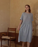 Woman drifting off in a breathable white cotton nightie, tag-free round neck and knee-length drape deliver spa-level softness for sensitive skin.