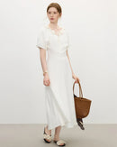 Woman posing in a pastel V-neck dress with textured puff sleeves, soft woven crepe drapes into a flattering midi length—perfect for spring brunches or daytime weddings.