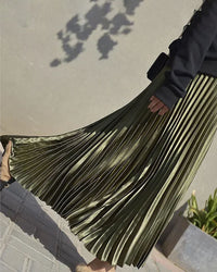 Woman twirling in a velvet high-waist pleated skirt, rich emerald pile catches the light while the 32-inch midi hem skims boots—your luxe statement for 50-70 °F fall-through-spring dinners.